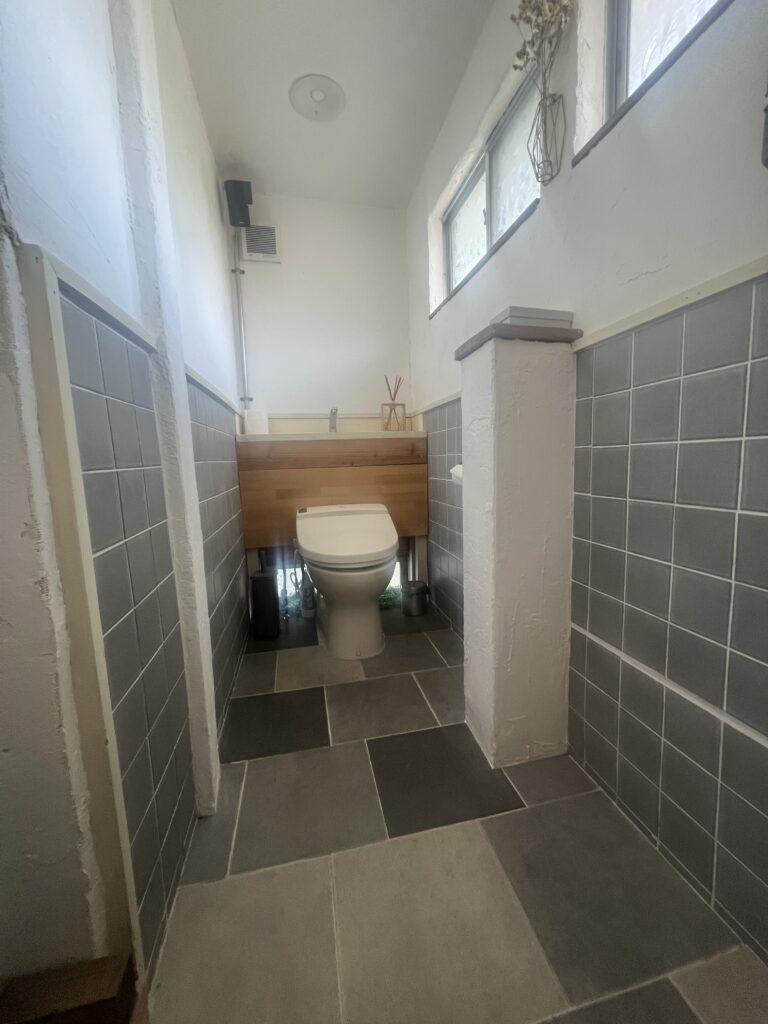 白壁とグレーのタイルで仕上げた清潔間のあるトイレ空間の完成後の様子