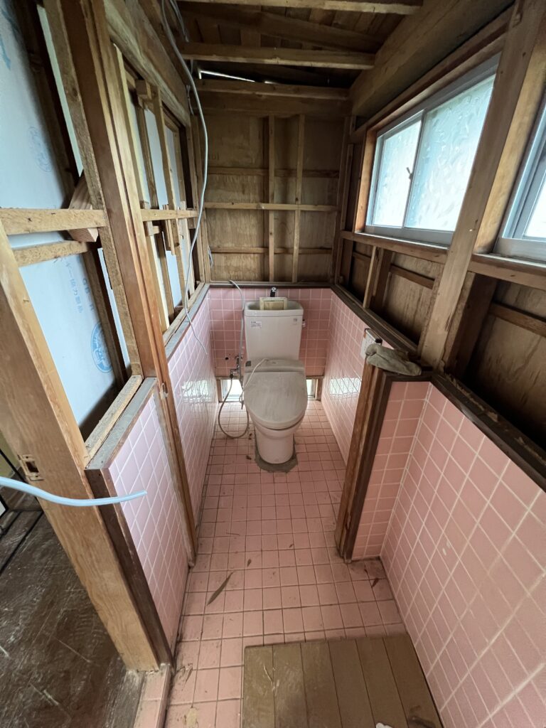 ピンク色のタイルで囲まれた施工前のトイレ全体の様子