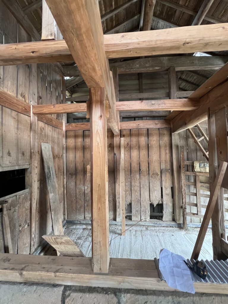 納屋の古い内壁のビフォー写真。板が割れ、経年劣化が見られる状態。