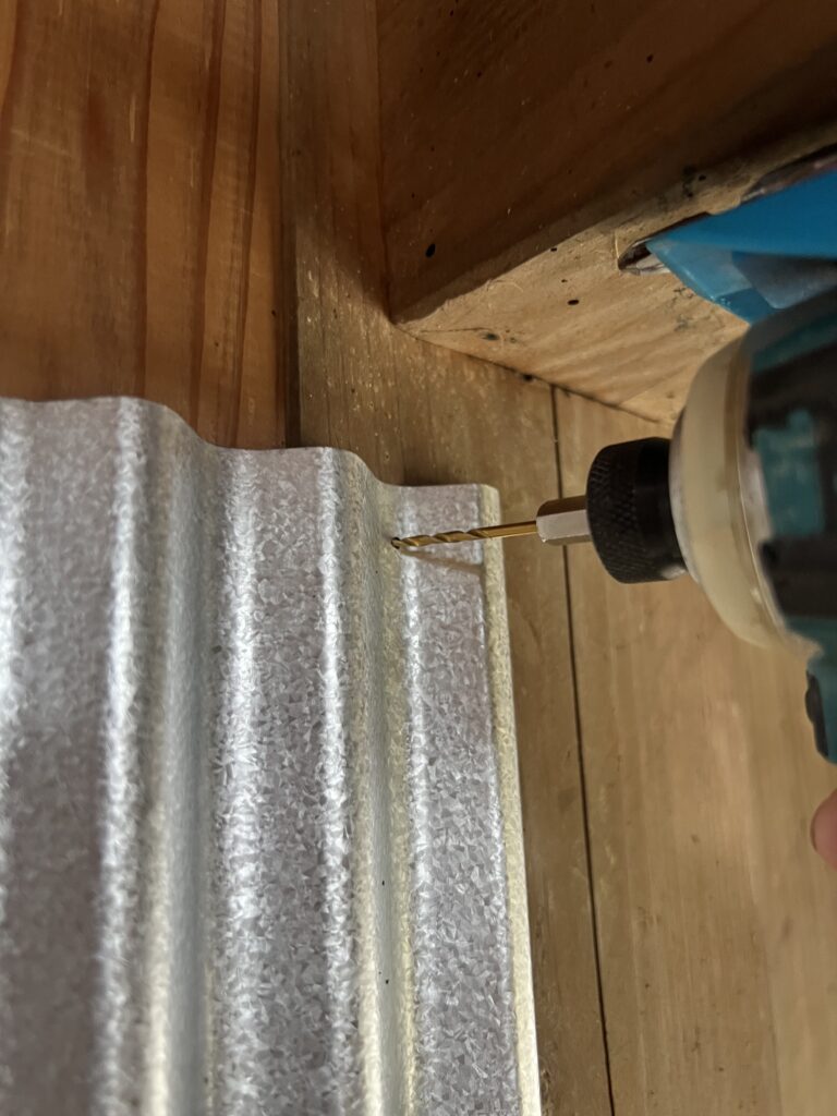 ドリルでガルバ波板に下穴を開けてビス打ちしているDIY作業の様子。
