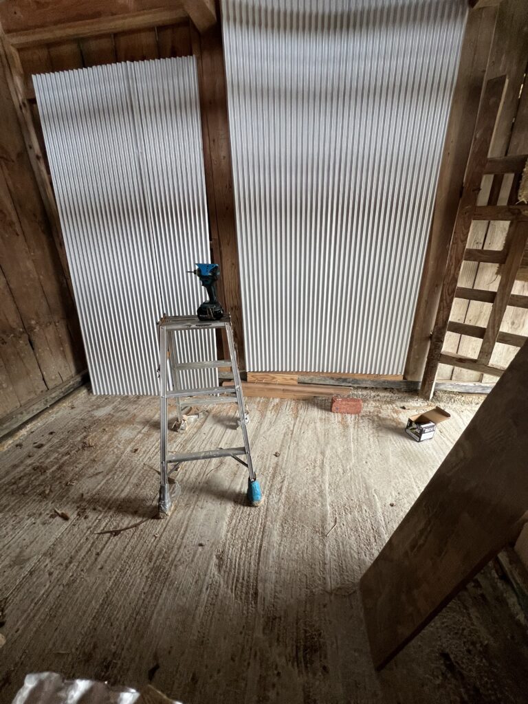 ガルバリウム波板を壁に貼り途中の様子。木枠に沿って慎重に施工中。