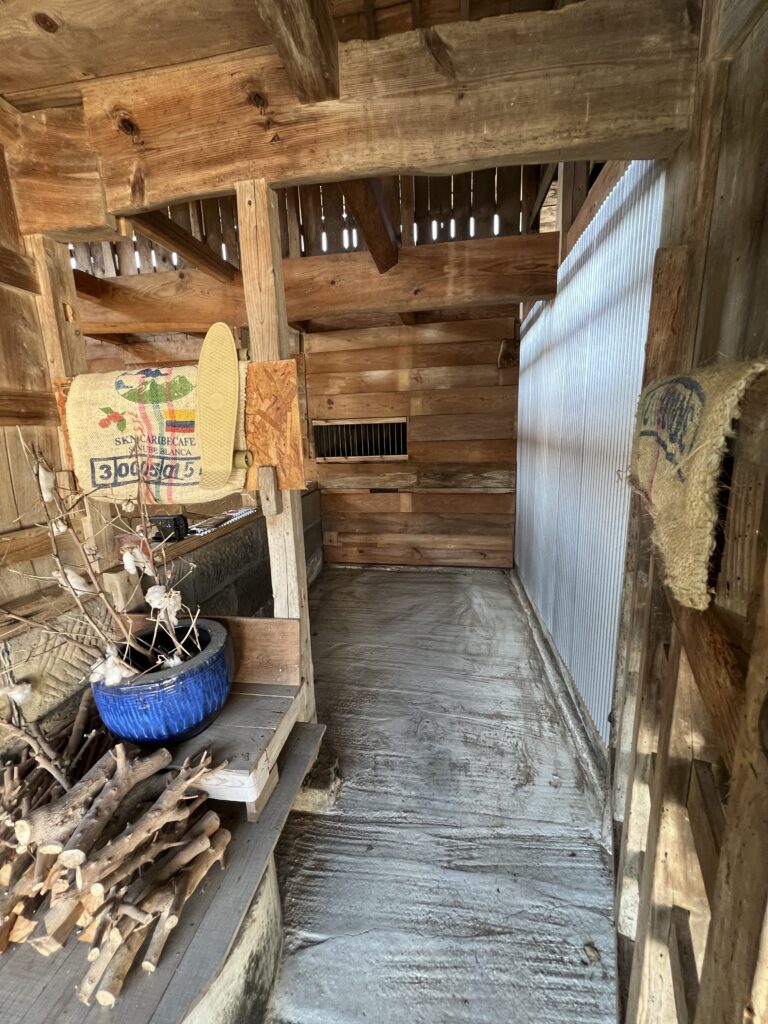 廃材と鉄筋、ガルバ波板を組み合わせた無骨なガレージの内壁。光が差し込み陰影が美しい完成写真。